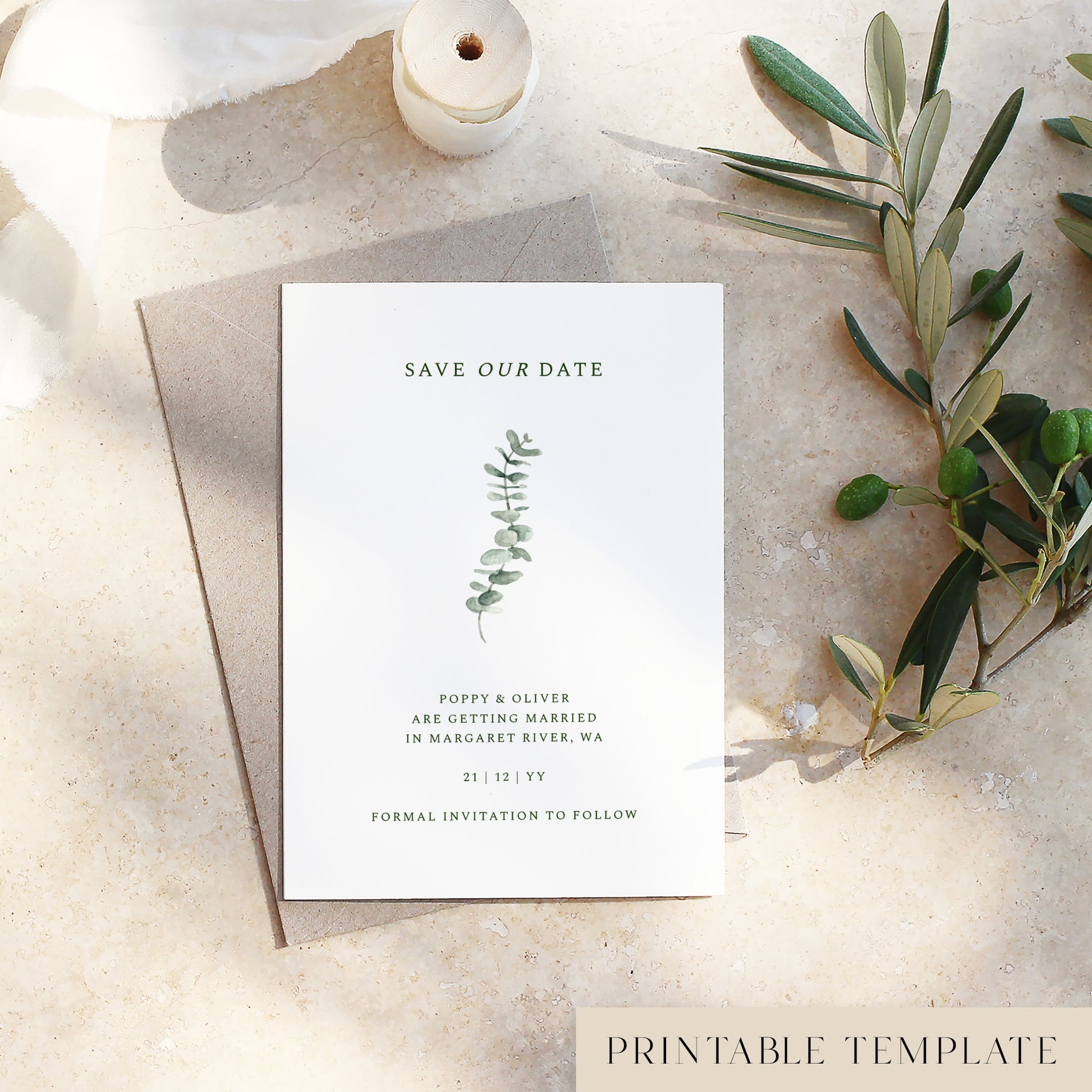 Save the date template with eucalyptus design printed on a white card sitting on a textured surface with olive branches.