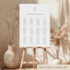 Printable minimal wedding seating chart sign on an easel with floral arrangements in a room setting.