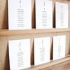 Set of six printable seating chart cards with names on a wooden display shelf.