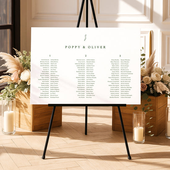 Modern seating chart template on an easel with floral arrangements and candles in a decorative setting.
