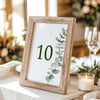 Wooden photo frame with a printed table number on a table setting with candles and glasses.