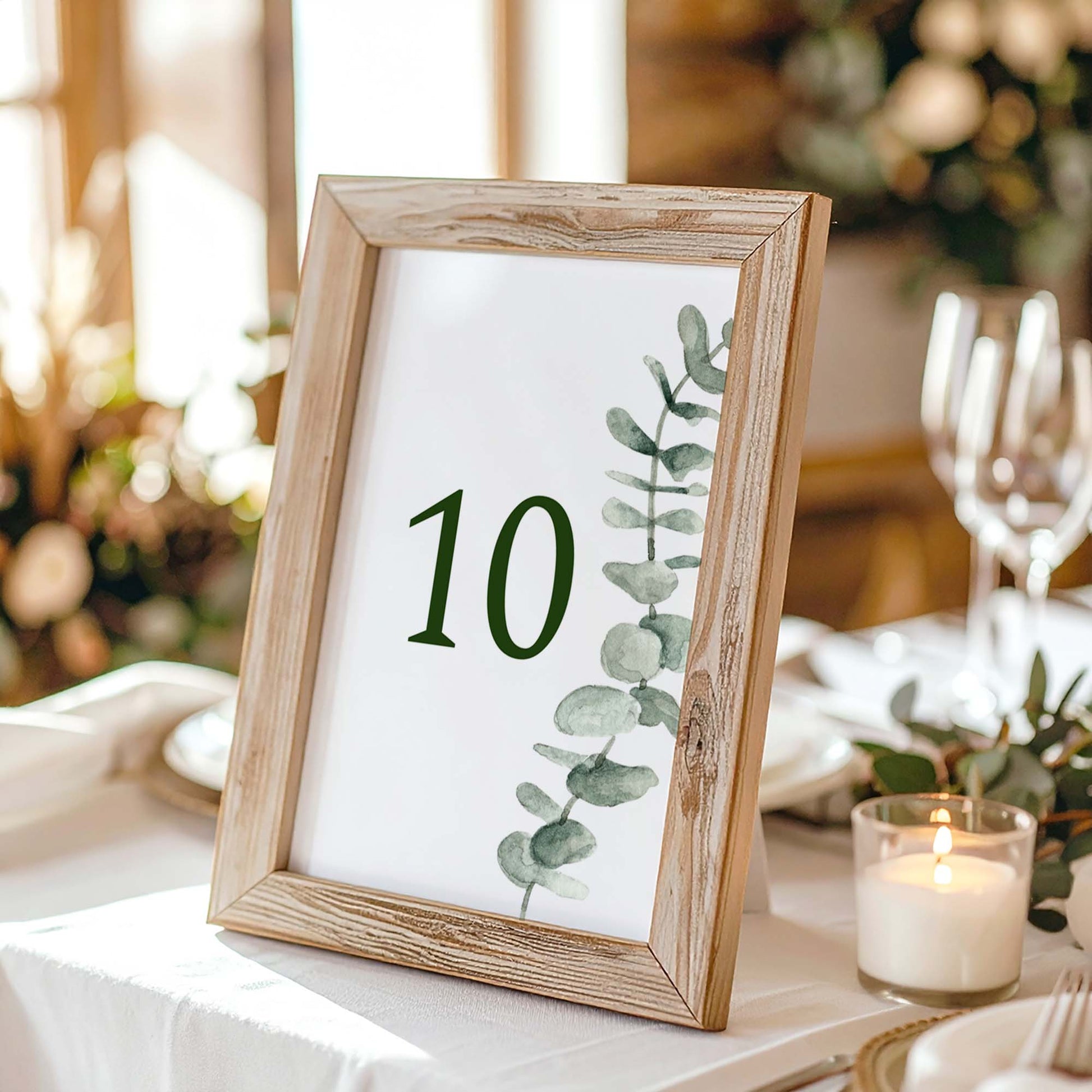 Wooden photo frame with a printed table number on a table setting with candles and glasses.