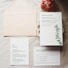 Greenery wedding invitation set with envelope, details card, and RSVP card on a textured surface.