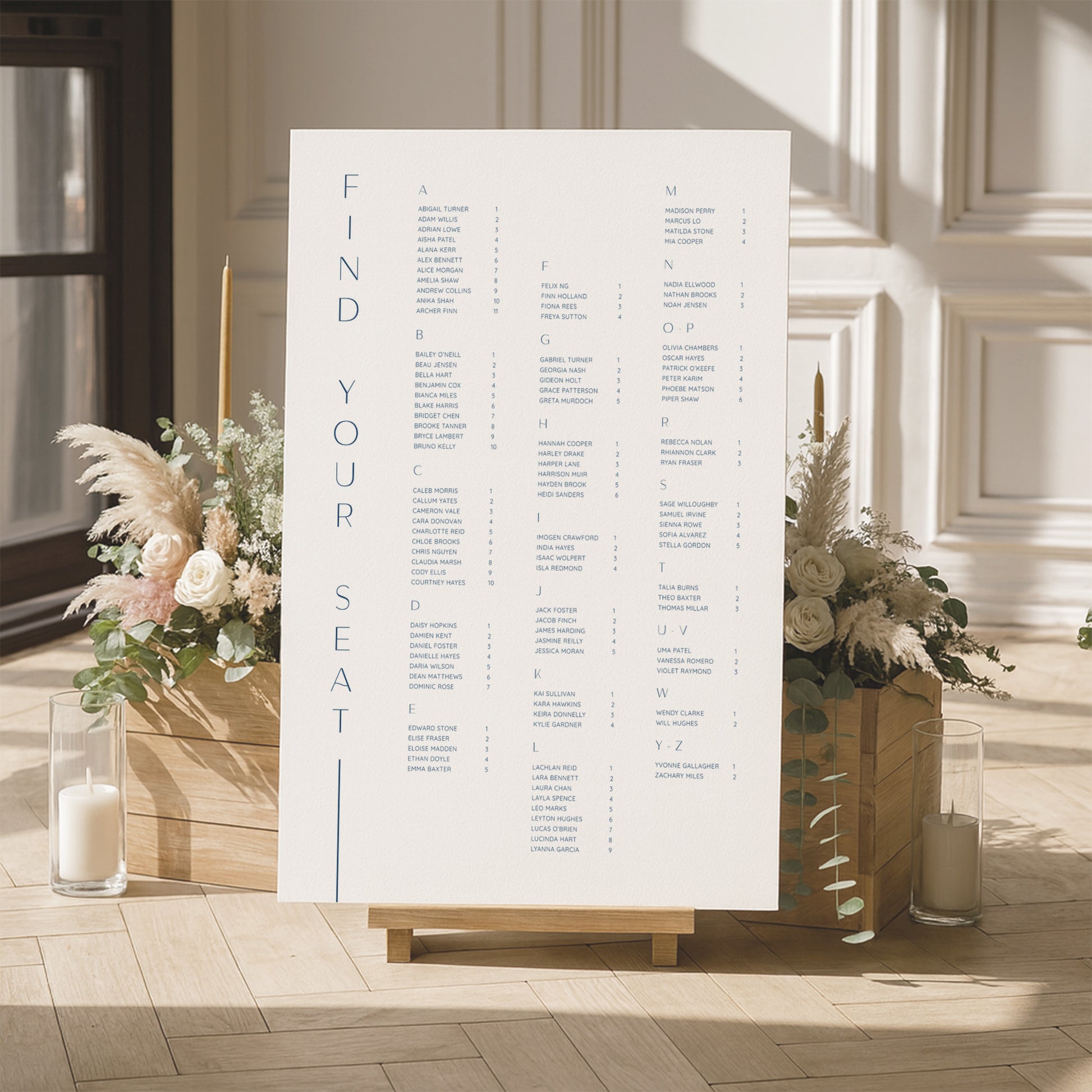 Modern alphabetical seating chart for a wedding with floral arrangements and candles in a room.