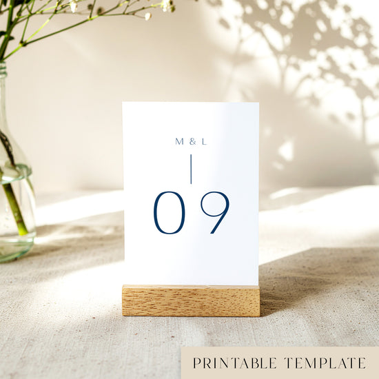 Printable table number card displayed on a wooden stand on a linen table cloth.