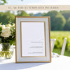 Framed wedding menu with floral arrangement on a table at an outdoors wedding.