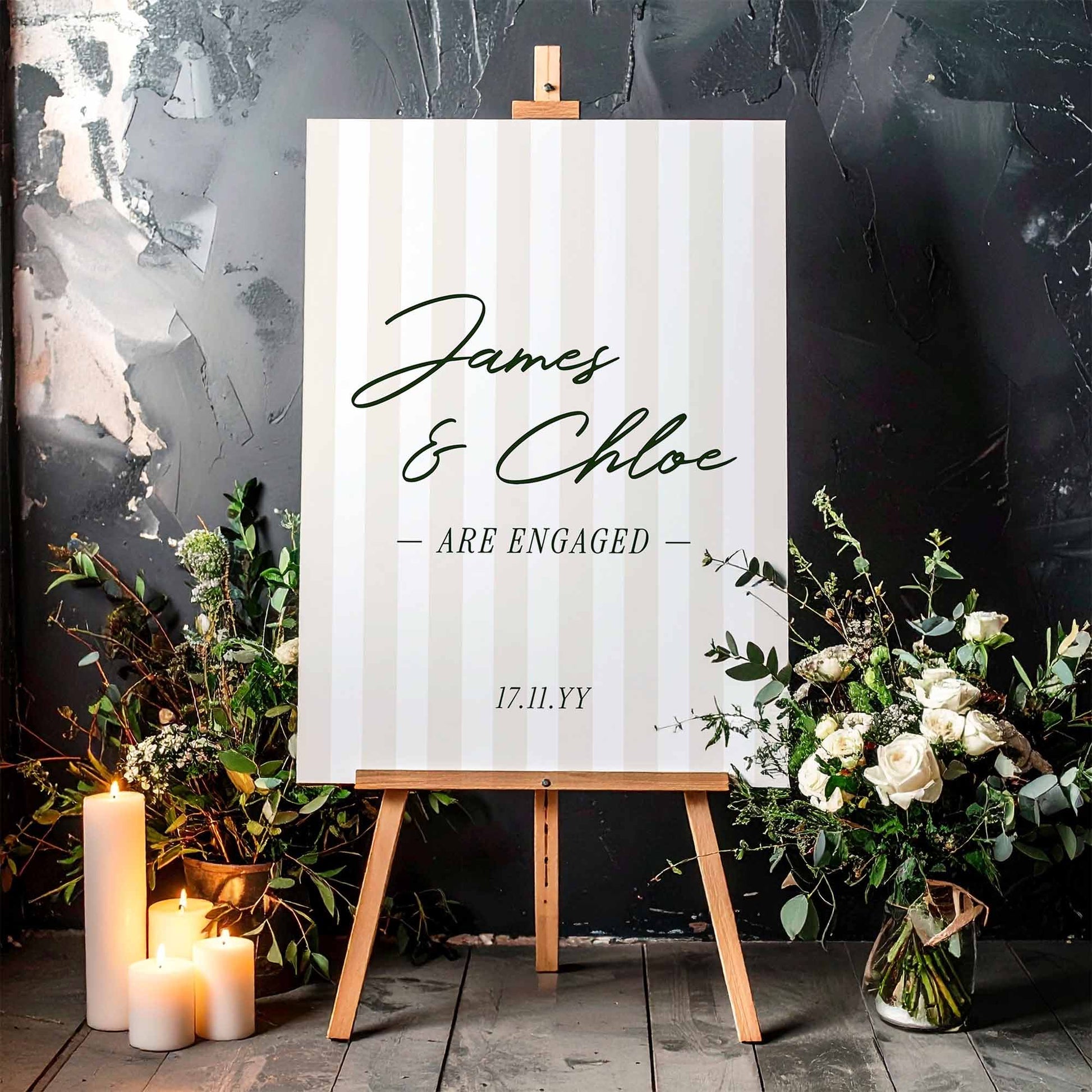 Preppy stripe engagement party sign on a wooden easel, surrounded by flowers and candles.