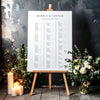 Printable alphabetical wedding seating chart sign on an easel with floral arrangements in a room setting.