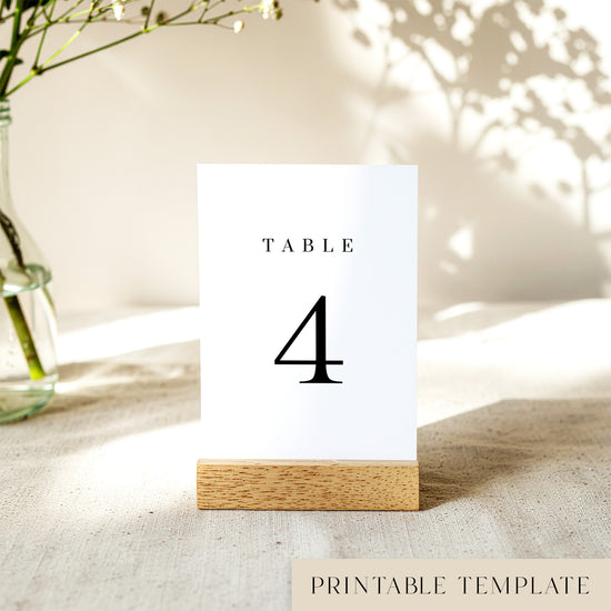Printable table number card displayed on a wooden stand on a linen table cloth.