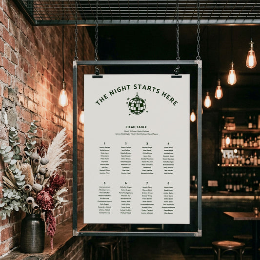 Casual wedding seating chart for 8 tables hanging in a moody bar with warm pendant lights