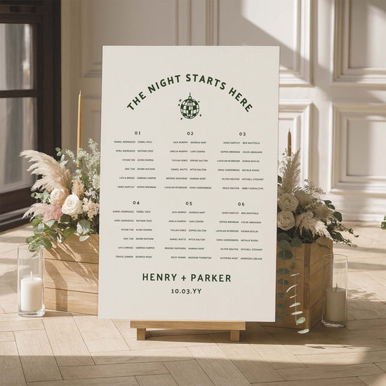 Long tables wedding seating chart with floral arrangements and candles in a room setting.