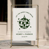 Retro-style wedding welcome sign with playful curved text and graphic disco ball detail, displayed on a gold stand against a warm neutral wall.