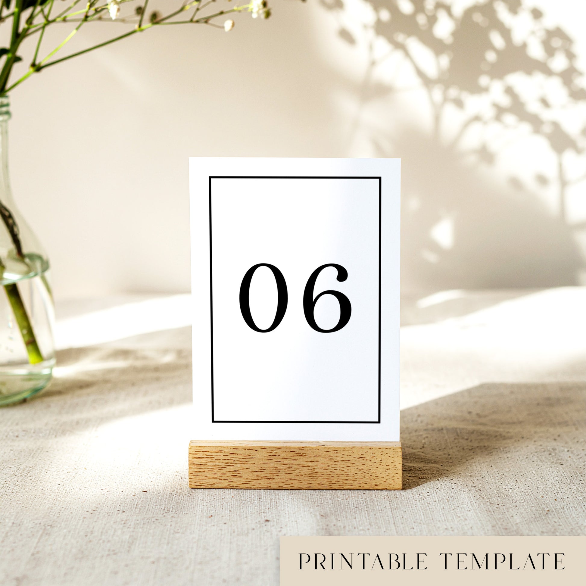 Printable table number card displayed on a wooden stand on a linen table cloth.
