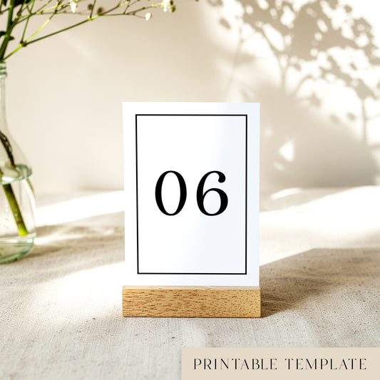 Printable table number card displayed on a wooden stand on a linen table cloth.