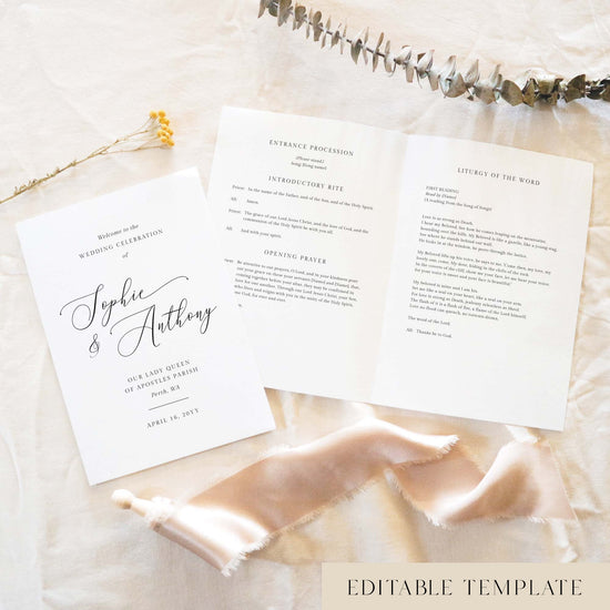 A5 wedding Mass ceremony booklet shown open with the cover beside it, styled on light fabric with dried florals and a soft ribbon.