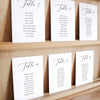 Set of six printable seating chart cards with names on a wooden display shelf.