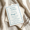 Whimsical hand-drawn bridal shower invitation template on textured card with envelope on fabric background.