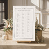 Modern alphabetical seating chart for a wedding with floral arrangements and candles in a room.