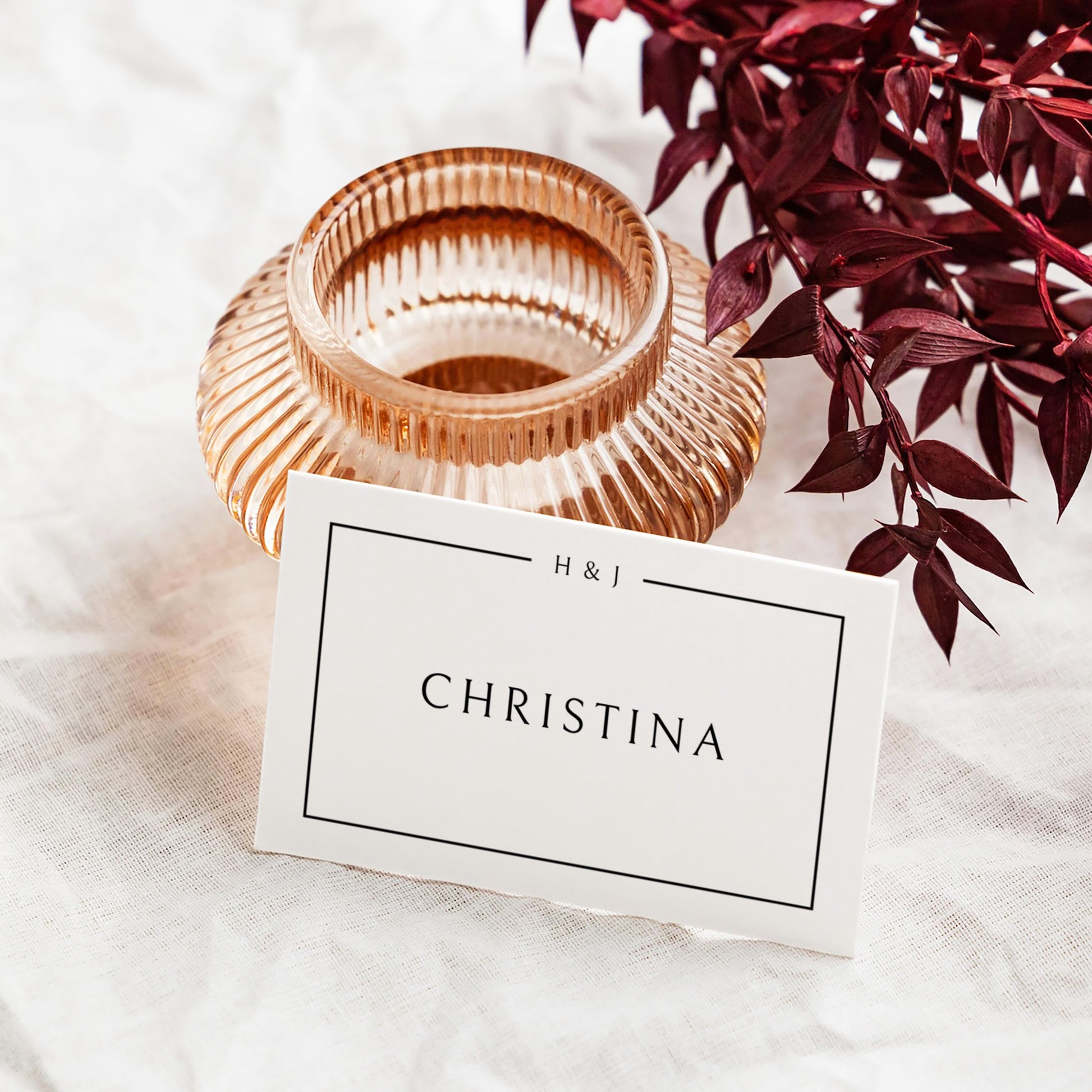 Rose gold candle holder with a flat place card leaning against it.