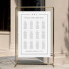Elegant wedding seating chart template displayed on a gold stand against a neutral wall.