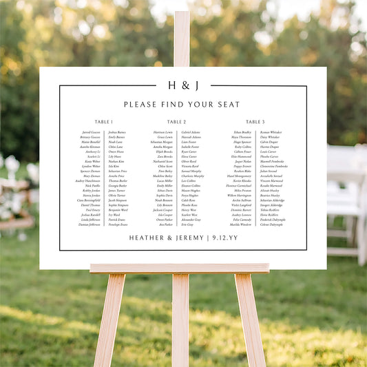 Horizontal wedding seating plan sign for long tables on an easel with a blurred outdoor ceremony background.