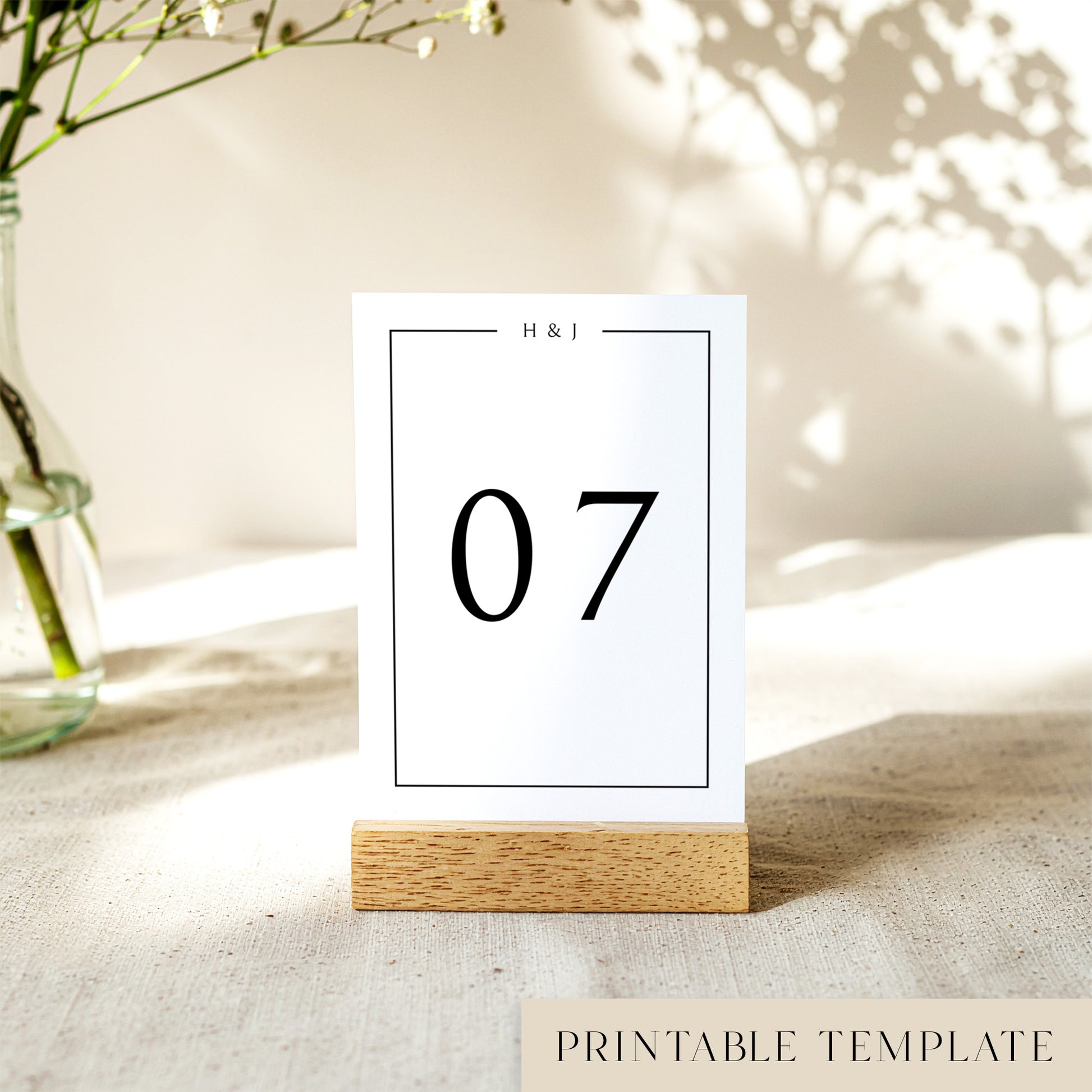 A printable table number template displayed on a small wooden block holder on a table with decorative items in the background.