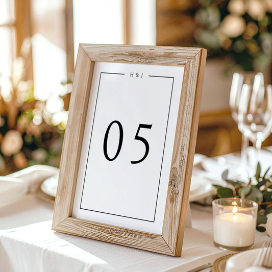 Wooden photo frame with a printed table number on a table setting with candles and glasses.