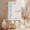 Editable editorial engagement party welcome sign on an easel with floral arrangements in a room setting.