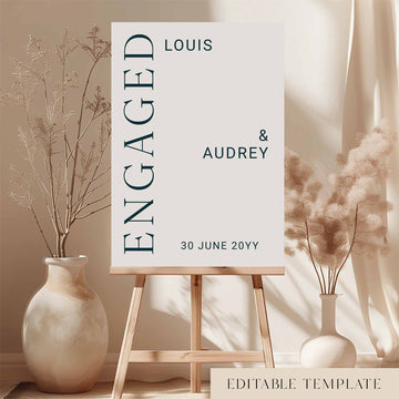 Editable editorial engagement party welcome sign on an easel with floral arrangements in a room setting.