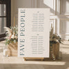 Micro wedding seating chart for 'FAVE PEOPLE' with floral arrangements and candles in a room setting.