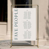 Wedding long tables seating plan with 'FAVE PEOPLE' text on a gold stand against a neutral wall.
