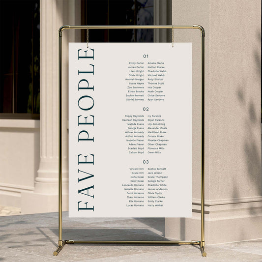 Wedding long tables seating plan with 'FAVE PEOPLE' text on a gold stand against a neutral wall.