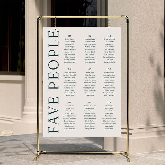 9-table seating chart poster with 'FAVE PEOPLE' text on a gold stand against a neutral wall.