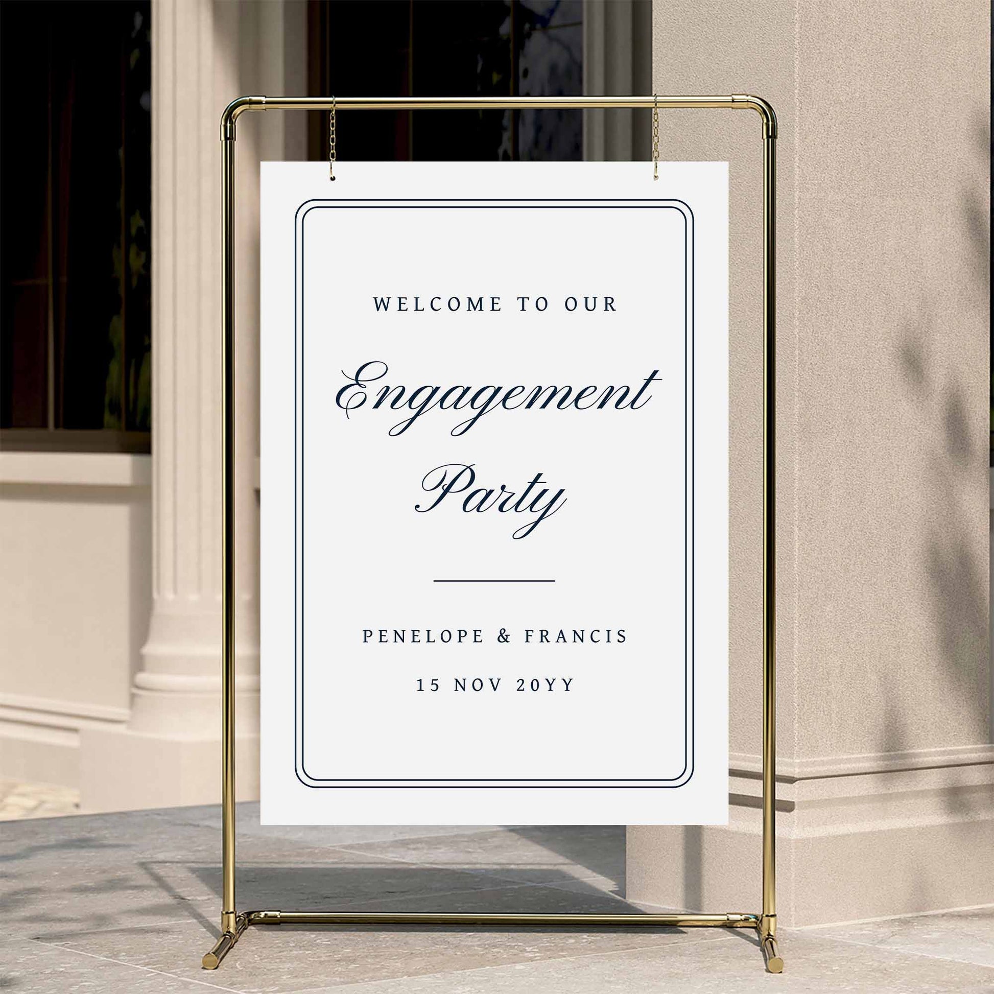 Classic engagement party welcome sign displayed on a gold stand against a neutral wall.
