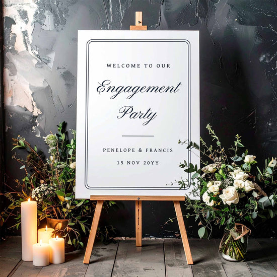Engagement party sign on an easel with floral decorations and candles against a dark background.