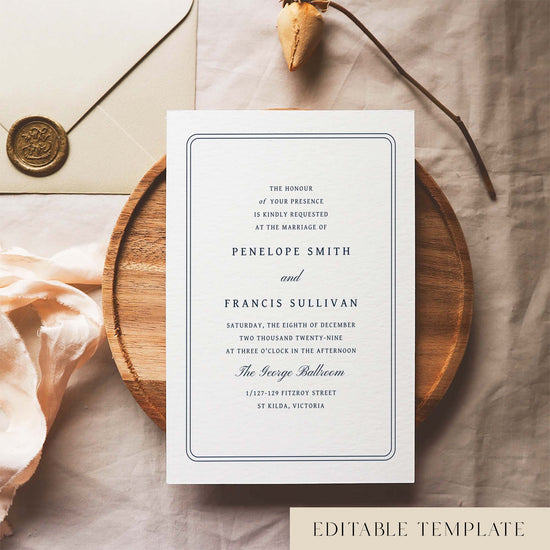 Wedding invitation template design on a white card sitting on a wooden plate with decorative elements.