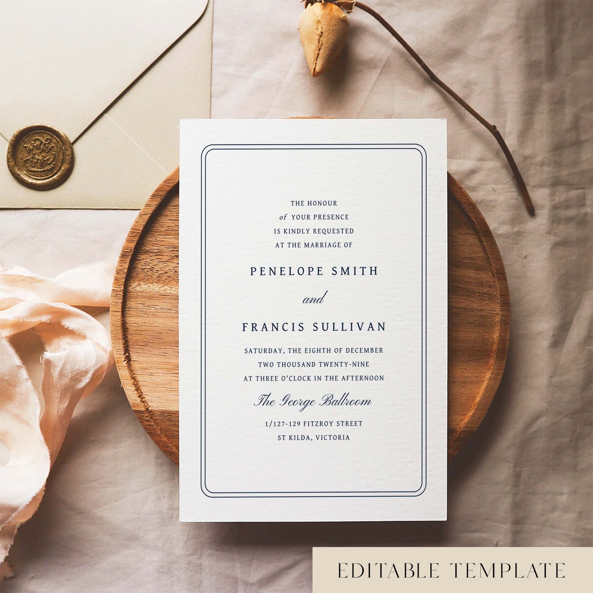 Wedding invitation template design on a white card sitting on a wooden plate with decorative elements.