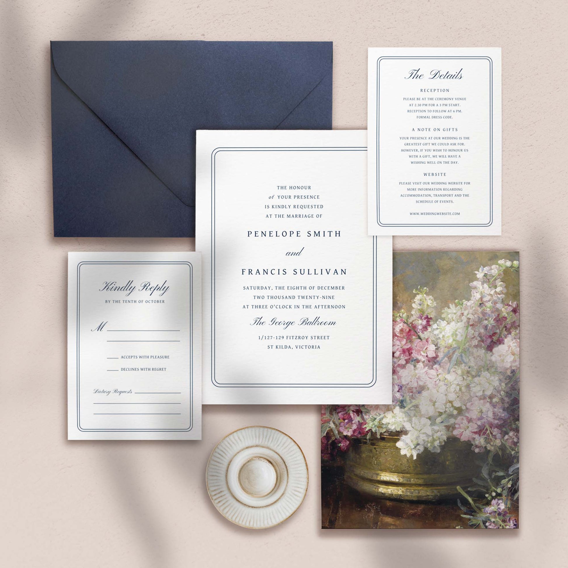 Wedding invitation, details card, RSVP card and envelope on a textured surface.