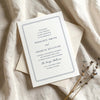 Wedding invitation card on textured card with envelope on fabric background.