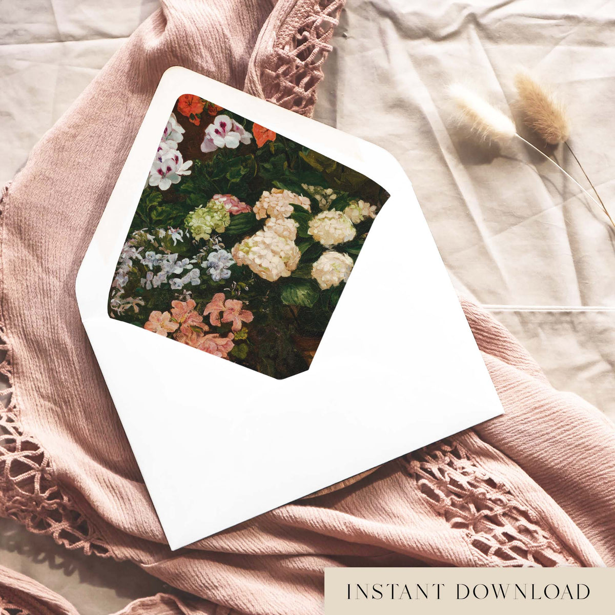 Printable cottage garden envelope liner for 5x7 wedding invitations, with painted cream hydrangeas, pink azaleas and white geraniums, shown inside a white envelope on dusty pink fabric.