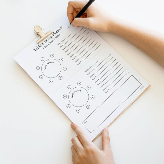 Person holding a table seating chart planner on a clipboard.