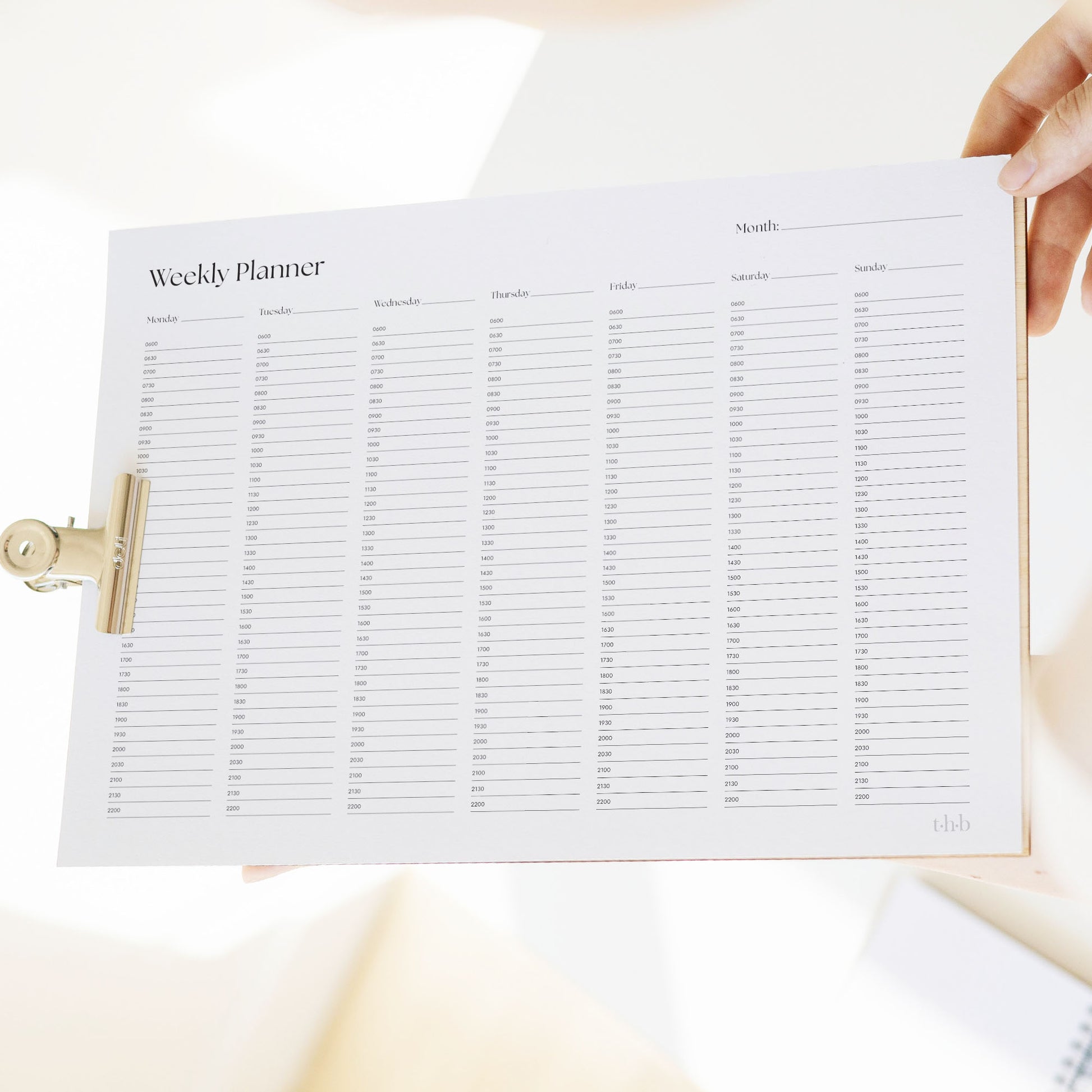 Weekly planner sheet on a clipboard held by a person.