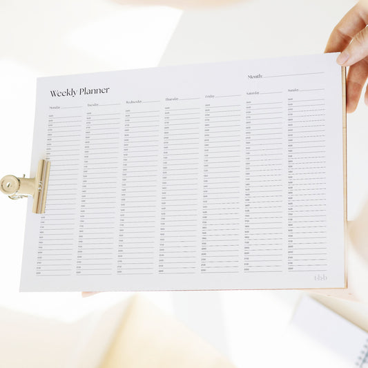 Weekly planner sheet on a clipboard held by a person.