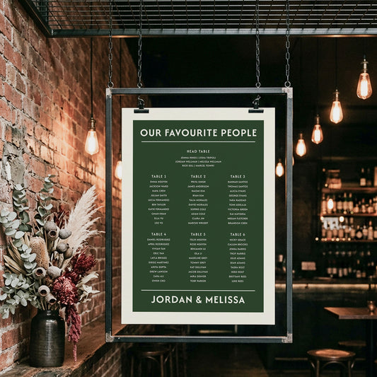 Industrial-style wedding guest list poster hanging in a brick-walled bar. This editable hunter green seating plan accommodates 6 tables and is designed for modern Australian weddings. Easy to personalise wording and names online.