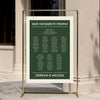 DIY bold forest green wedding seating chart template hanging from a gold frame at a modern city venue.