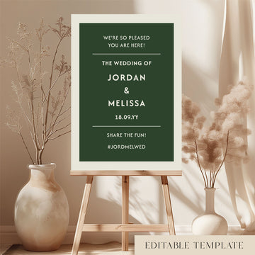 DIY wedding welcome sign template in forest green and cream displayed on a wooden easel. Features the Renard minimalist design in a bright, modern room with dried botanicals. Printable A1 or A2 size by The Hello Bureau.