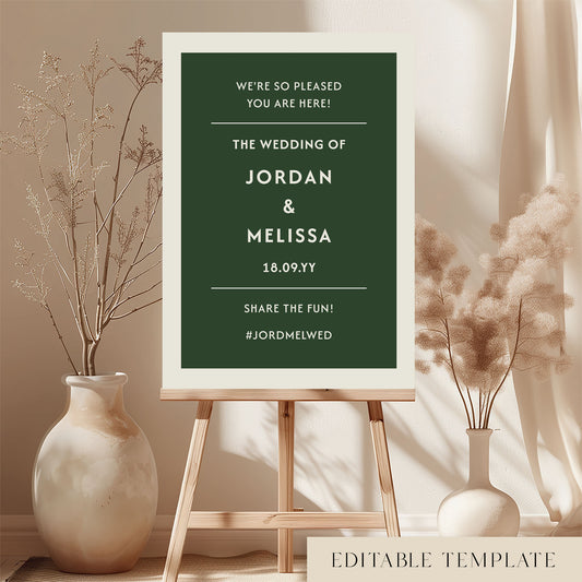 DIY wedding welcome sign template in forest green and cream displayed on a wooden easel. Features the Renard minimalist design in a bright, modern room with dried botanicals. Printable A1 or A2 size by The Hello Bureau.