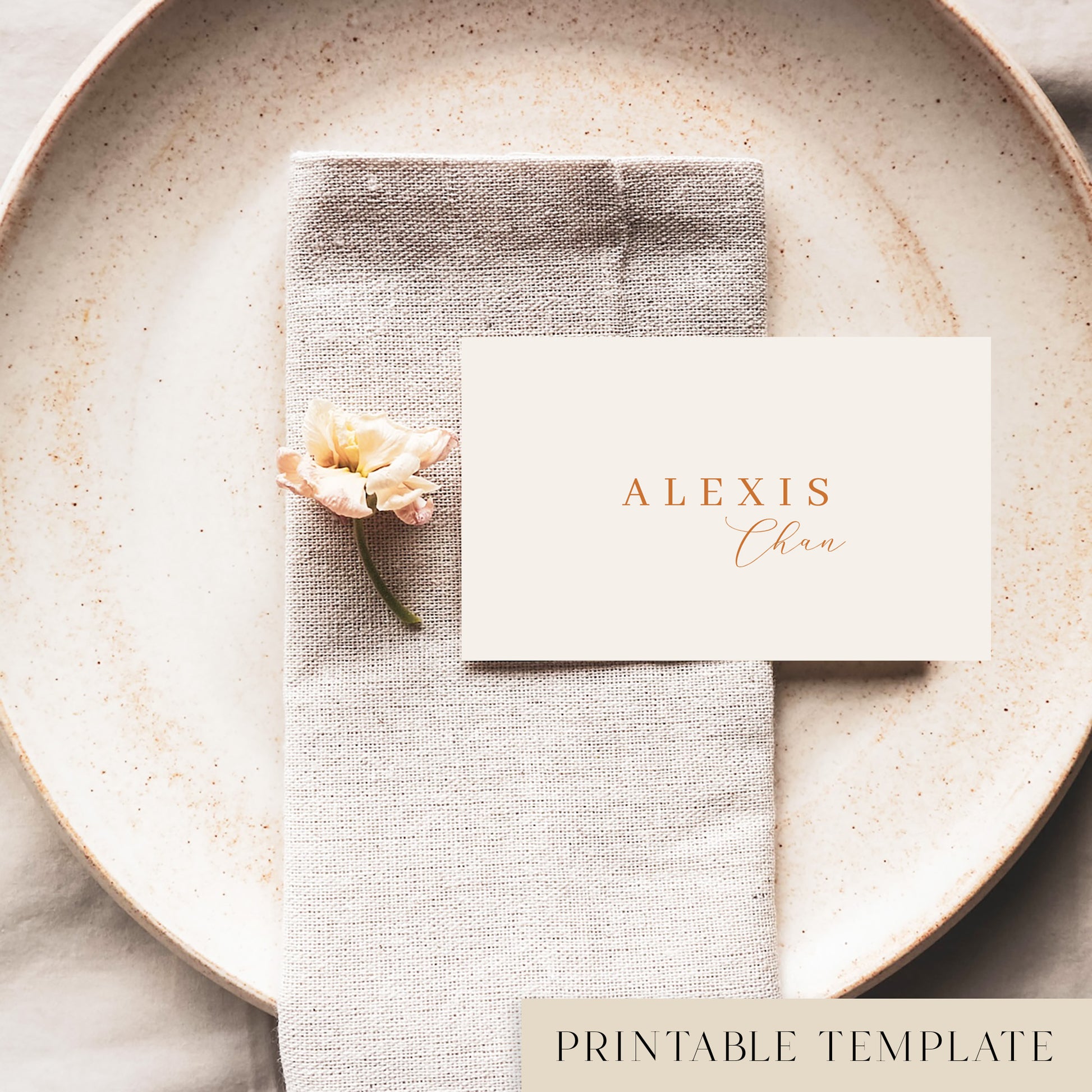 A flat place card with a name printed on it, positioned on a plate with a napkin and a floral decoration.