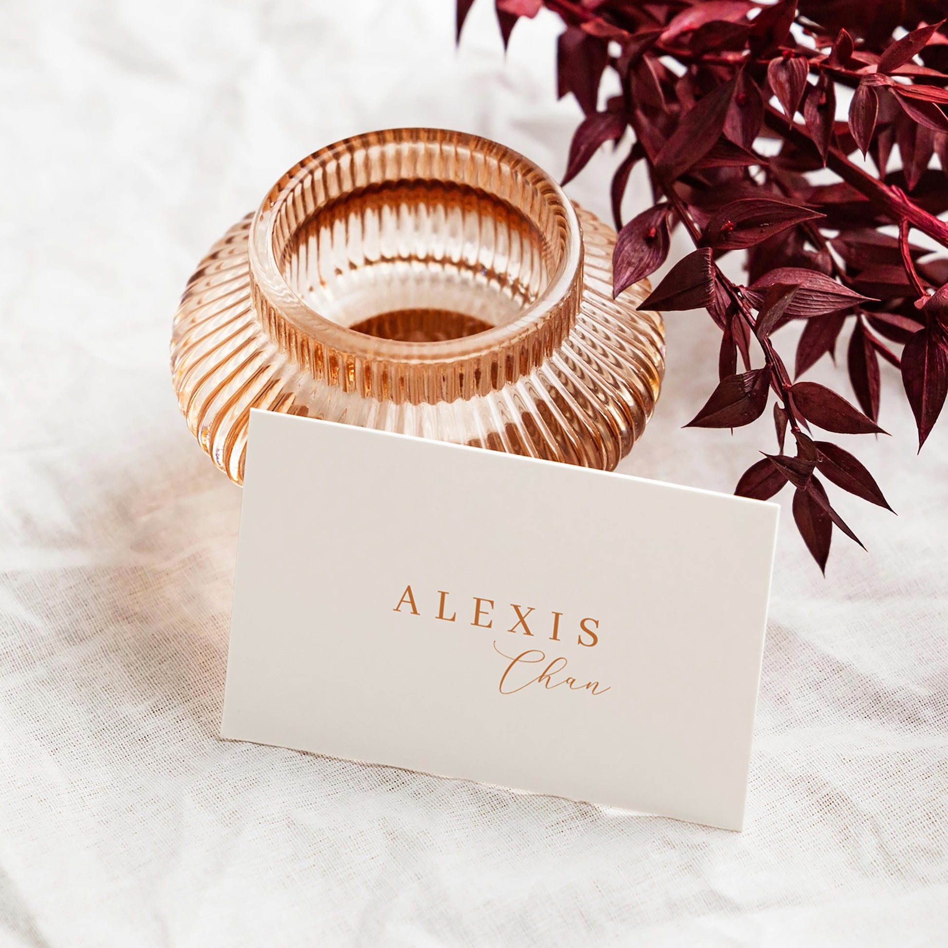Rose gold candle holder with a place card leaning against it.