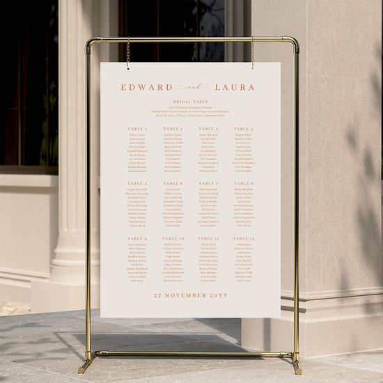 Minimal wedding seating chart template displayed on a gold stand against a neutral wall.